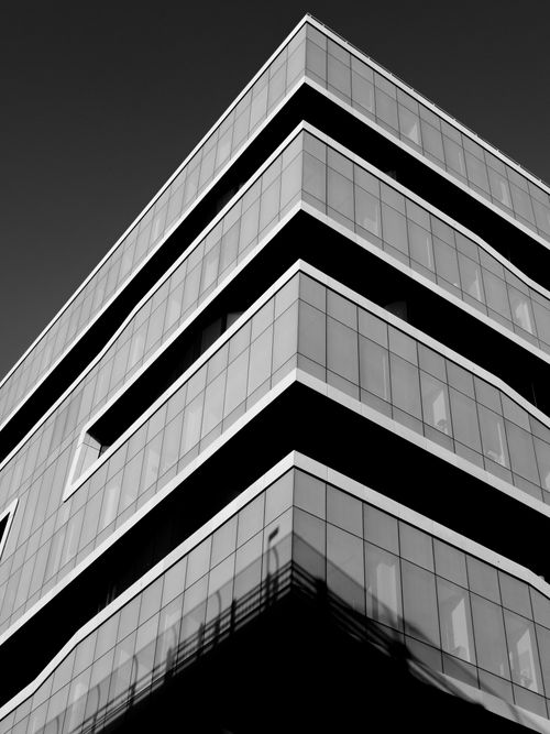 Free Monochrome image showcasing a sleek and angular glass skyscraper with striking architecture. Stock Photo