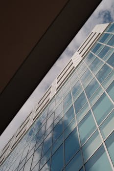 Low angle view of a modern skyscraper with a reflective glass facade against the sky.