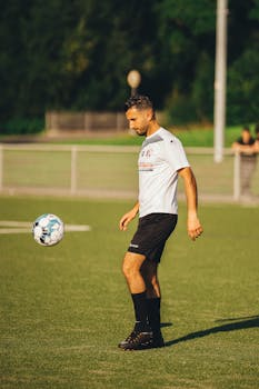 Athlete focusing on soccer ball control during practice on a sunny outdoor field.