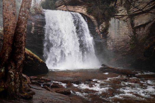 A stunning waterfall cascading over rugged rocks in a tranquil forest environment.