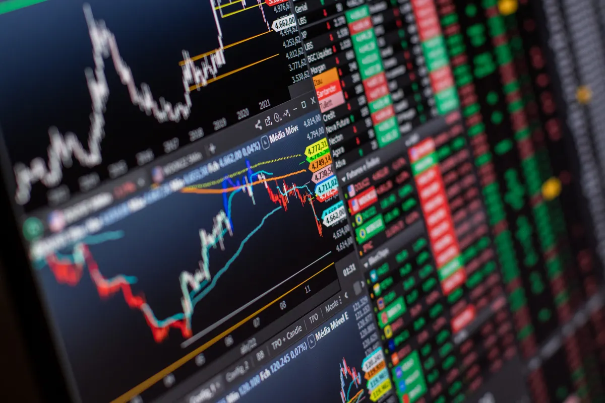 Stock market charts and performance data displayed across a monitor, representing forward-testing results before going live.