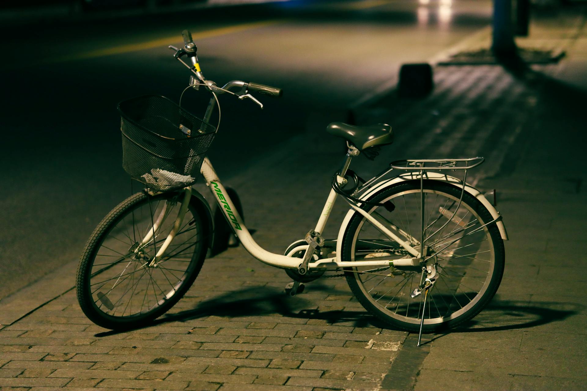 A bicycle is parked on a quiet street in Hangzhou, China at night.