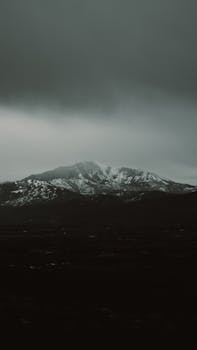 Moody view of a snow-capped mountain under dark skies in Eden, Utah.