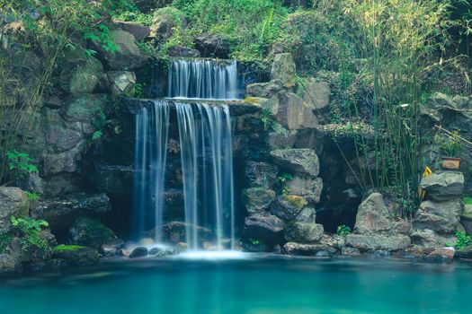 A tranquil waterfall cascading over rocks in a lush forest near Hangzhou, China.
