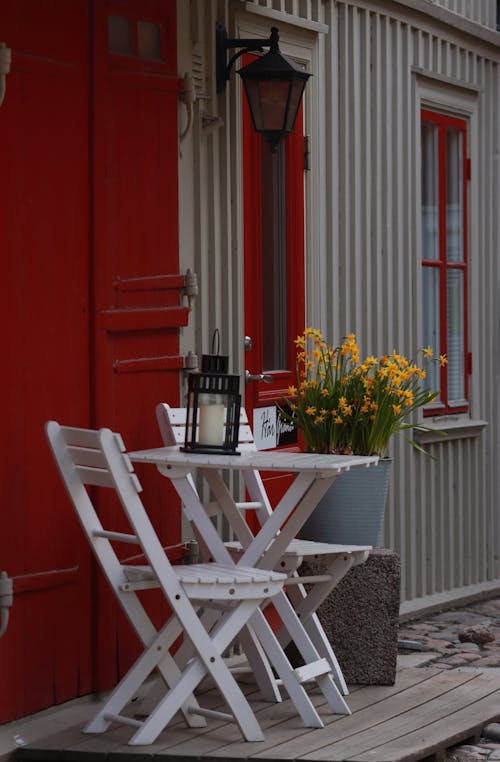 White Wooden Chairs and Table Near Red Wall