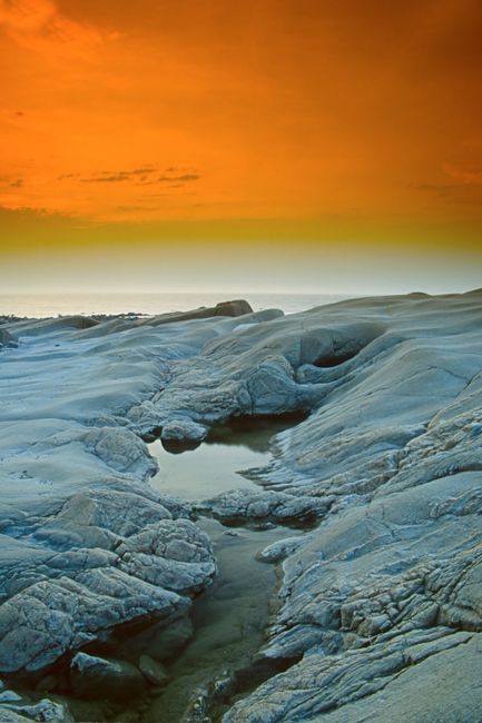 Breathtaking view of rock formations against an orange sunset sky.