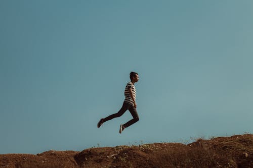 Free Man Jumping Near the Cliff Stock Photo