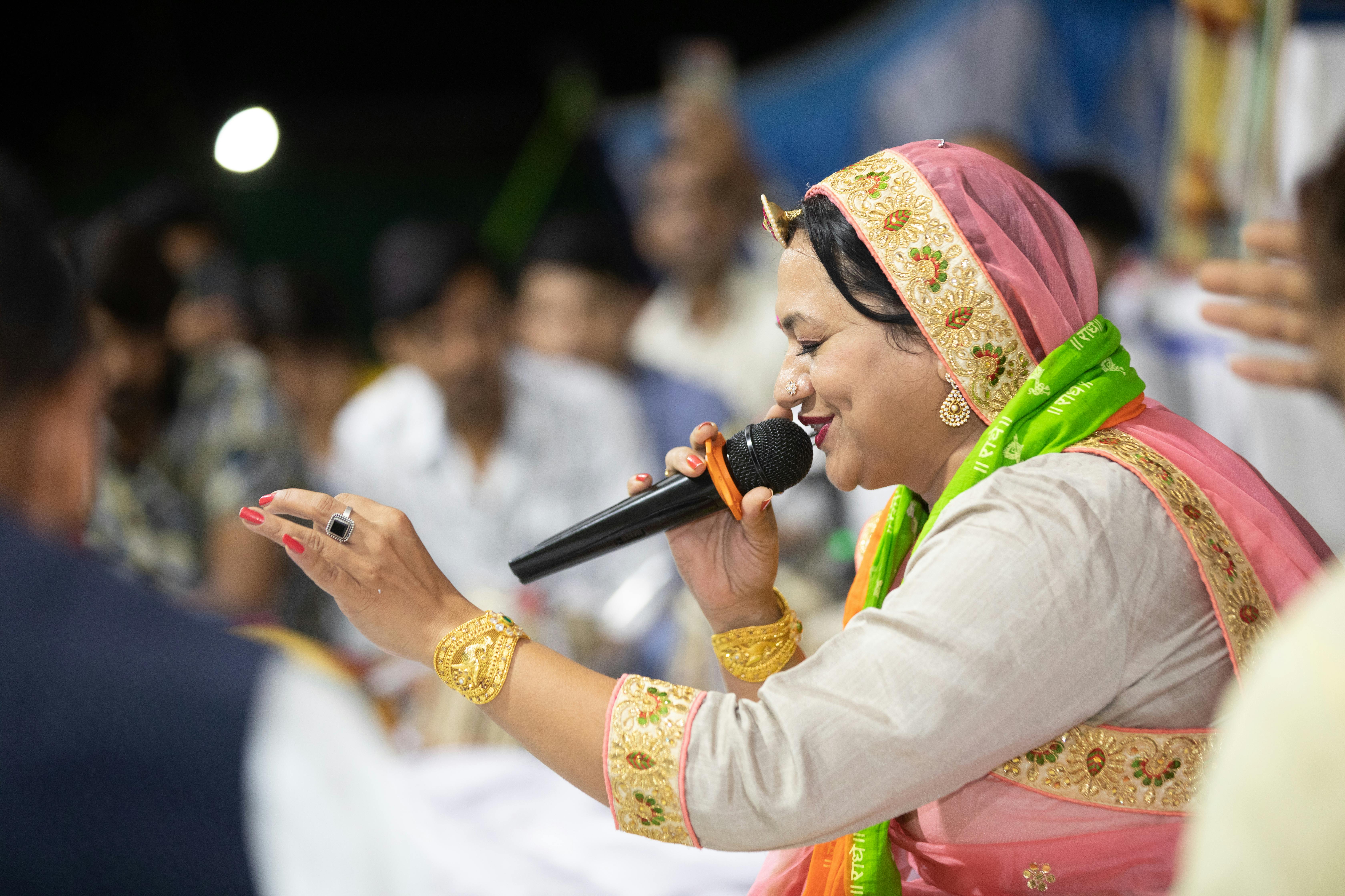 a woman wearing headscarf while singing using a microphone