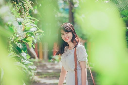 一位女士在户外微笑着，享受绿树环绕、阳光明媚的一天