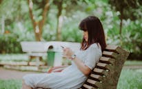 Woman Sitting on Bench Checking Her Phone
