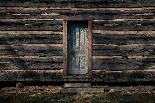 Free A rustic wooden door on a vintage cabin wall showcasing weathered texture and natural wood patterns. Stock Photo
