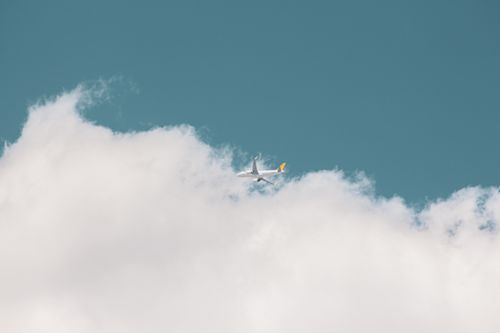 Free Aerial view of an airplane flying above clouds in a clear blue sky, capturing the essence of travel and freedom. Stock Photo