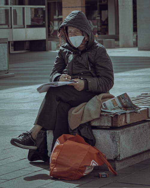 Free Woman in Black Coat Sitting on Concrete Bench Reading Book Stock Photo