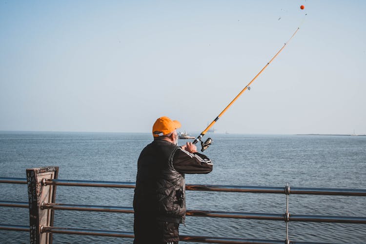 A Man In Black Jacket Fishing On The Sea