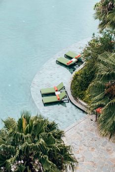 Relaxing poolside scene with lounge chairs and palm trees, capturing a serene vacation vibe.