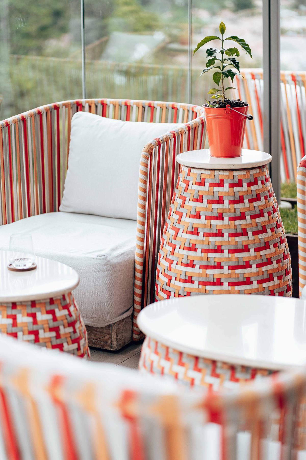 Bright outdoor seating area featuring woven wicker furniture and a vibrant potted plant. Stock Photo.