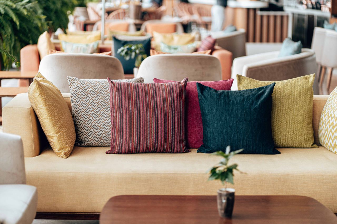 Beige sofa with colorful yellow red and teal throw pillows