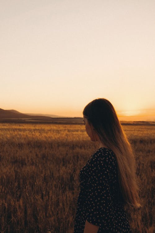 A Woman in Printed Long Sleeves Standing on Brown Grass Field