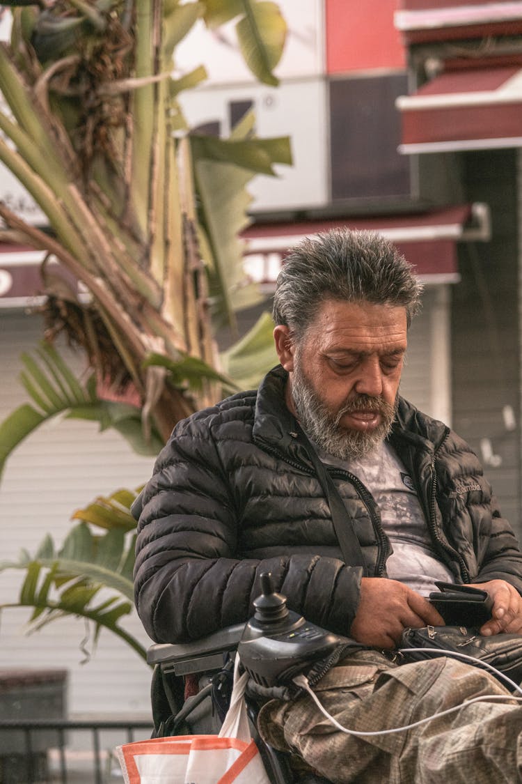 A Man In Black Puffer Jacket Sitting On The Wheelchair