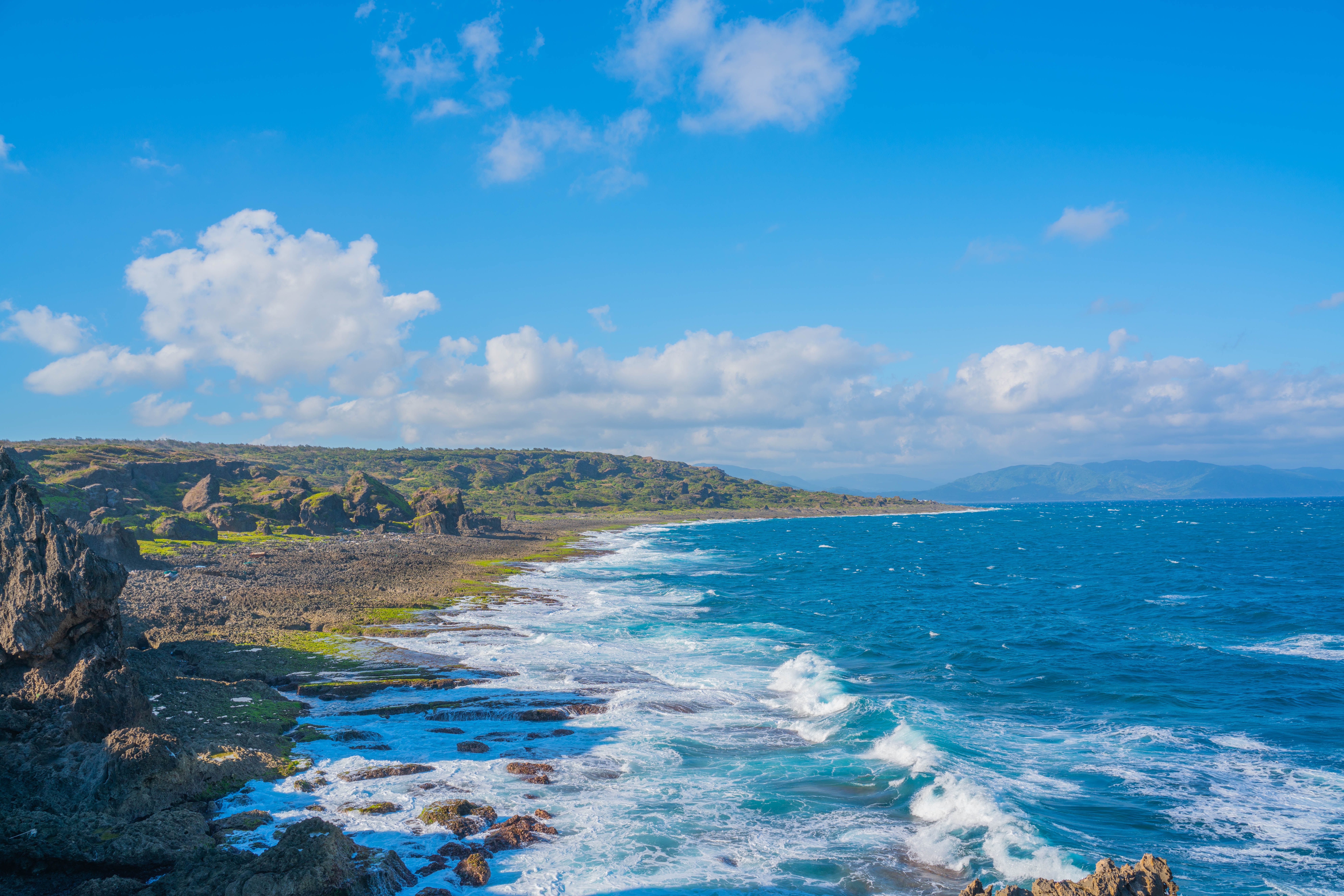 Breathtaking aerial view of Taiwan's rocky coastline with azure sea and white clouds, capturing nature's beauty.