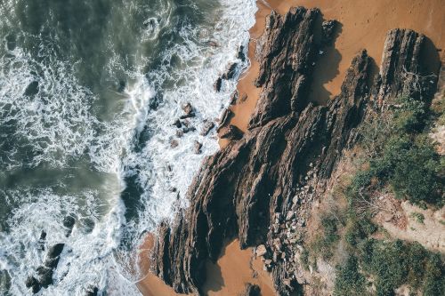 Free Top down view of rocky coastline with waves crashing on the shore, showcasing natural beauty. Stock Photo