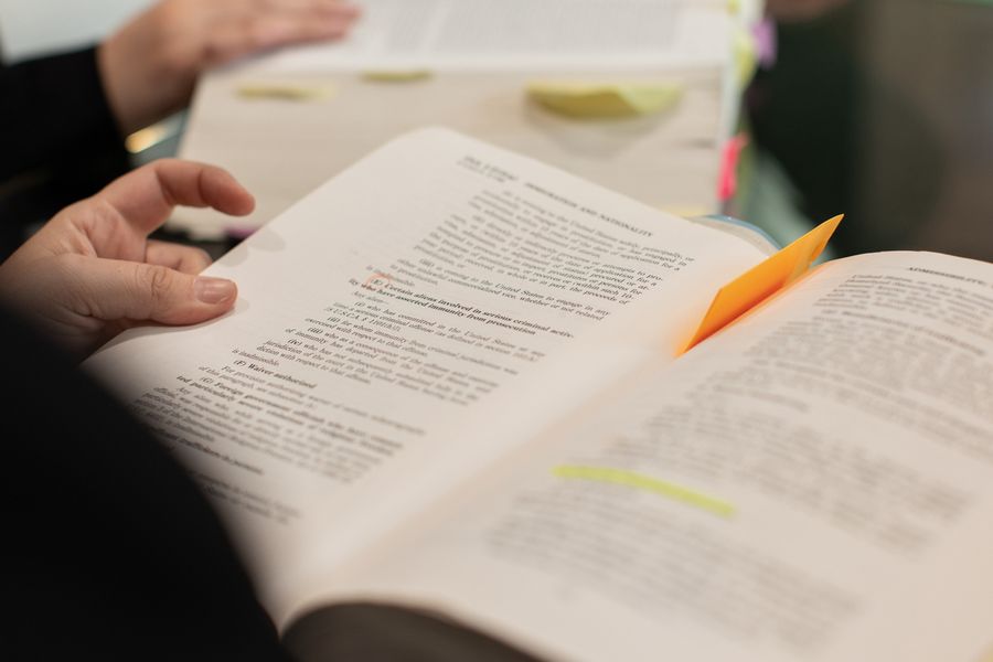 A close-up of hands holding books with highlighted text and notes, symbolizing learning and study.