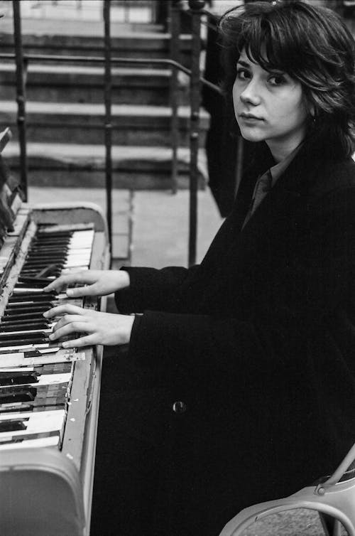 Grayscale Photo of Woman Playing Piano