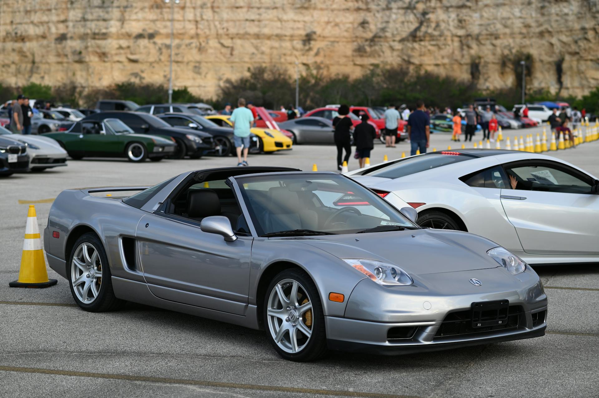 Silver sports car with convertible top at a San Antonio car meet in a parking lot.