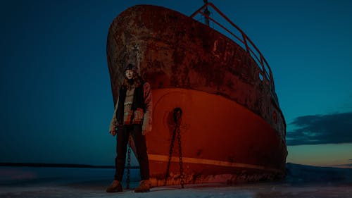 Free Woman Standing in Front of Ship on Seashore Stock Photo