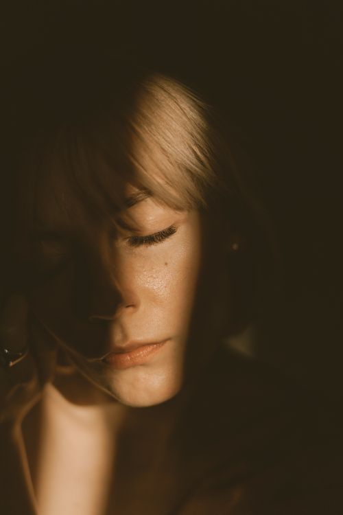 Free A serene portrait of a woman with closed eyes and dramatic lighting, creating a moody atmosphere. Stock Photo