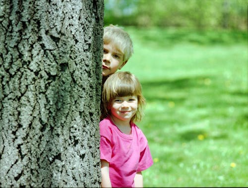 Boy and a Girl Standing Behind a Tree