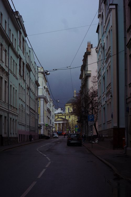 Free Quiet urban street with classical architecture leading to a historical building under moody skies. Stock Photo