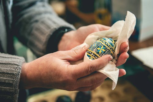 A Person Wiping a Ukrainan Pysanky Egg