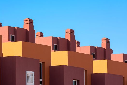 Vibrant geometric architectural structures with bold colors against a clear blue sky.