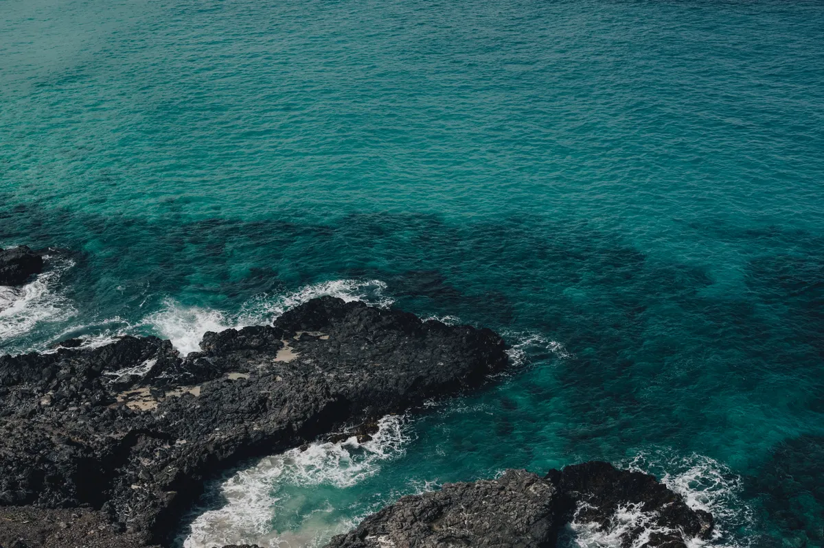 Oahu lava-rock coastline dropping straight into deep blue ocean