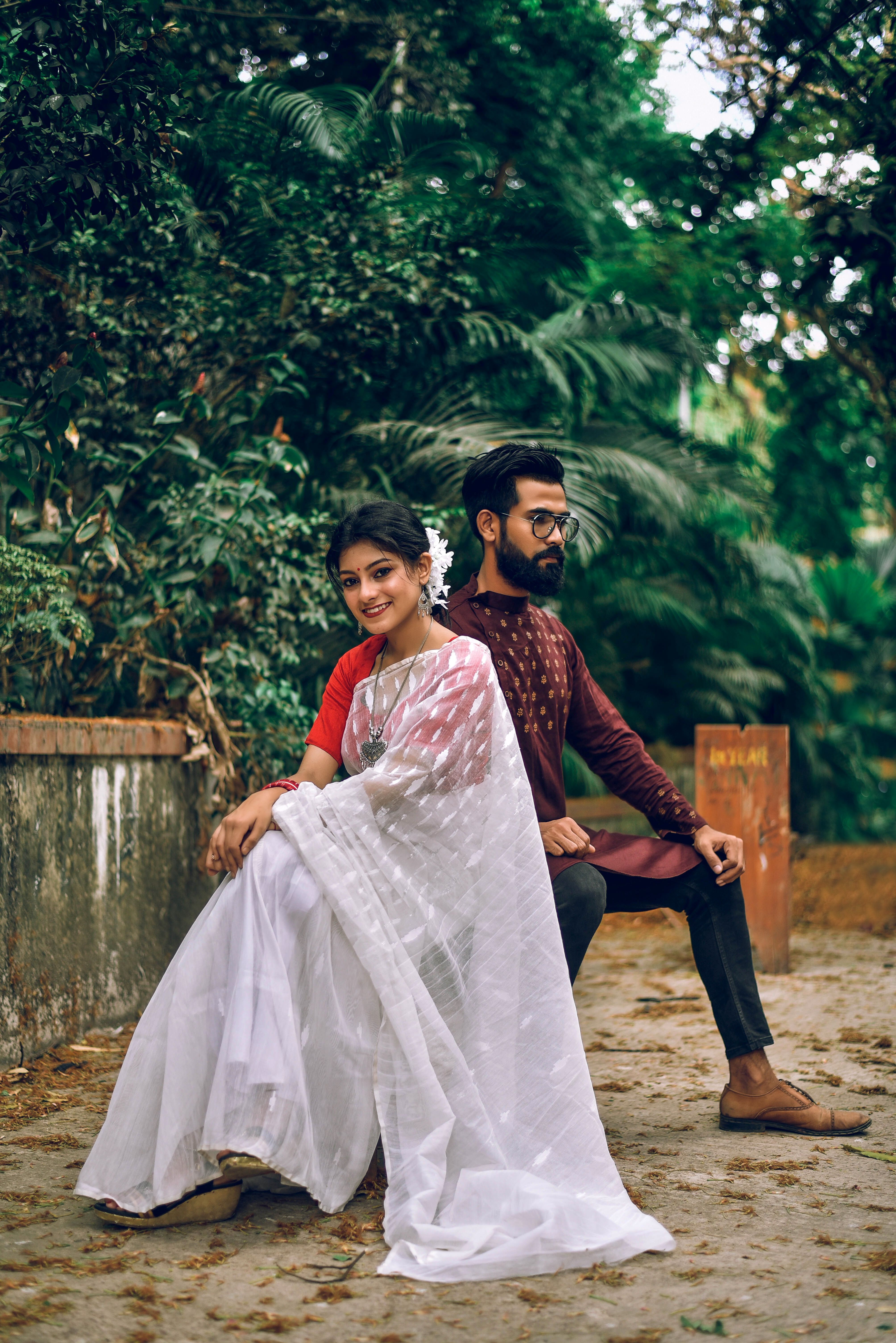 Beautiful couple in traditional South Asian attire sitting outdoors, capturing a moment of elegance and joy.