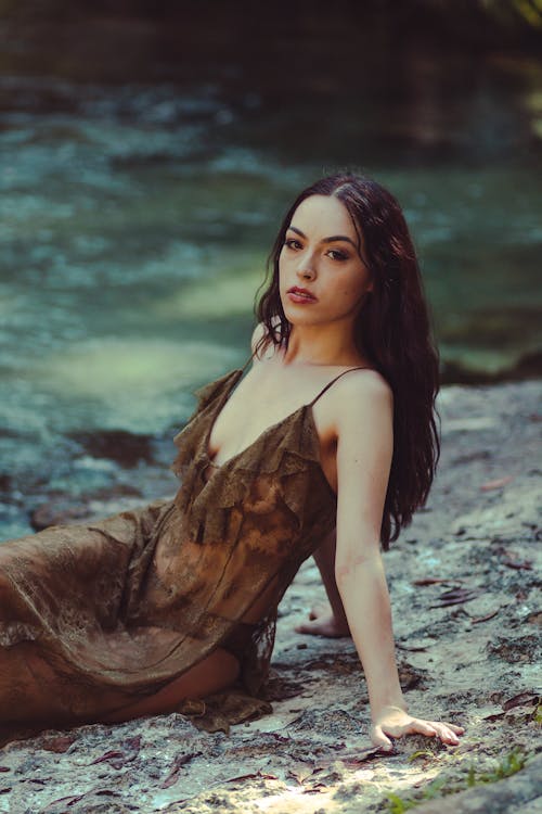 Woman in Brown Dress Sitting on the Lakeshore