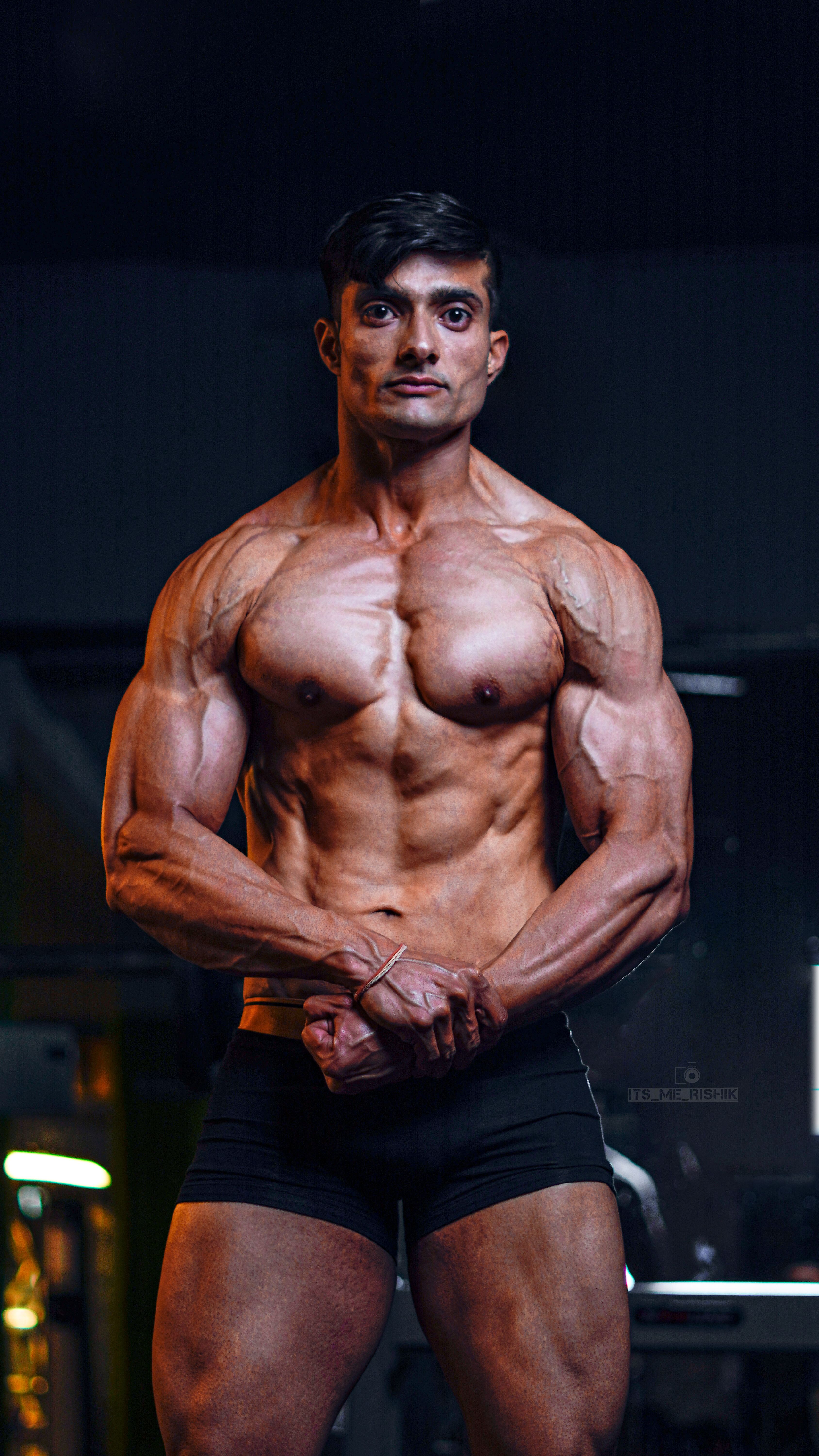 Athletic male fitness model showing muscular definition in gym lighting