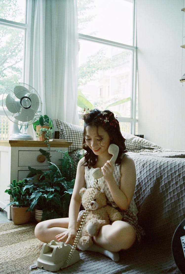 Young Girl Sitting On Floor Using Rotary Phone