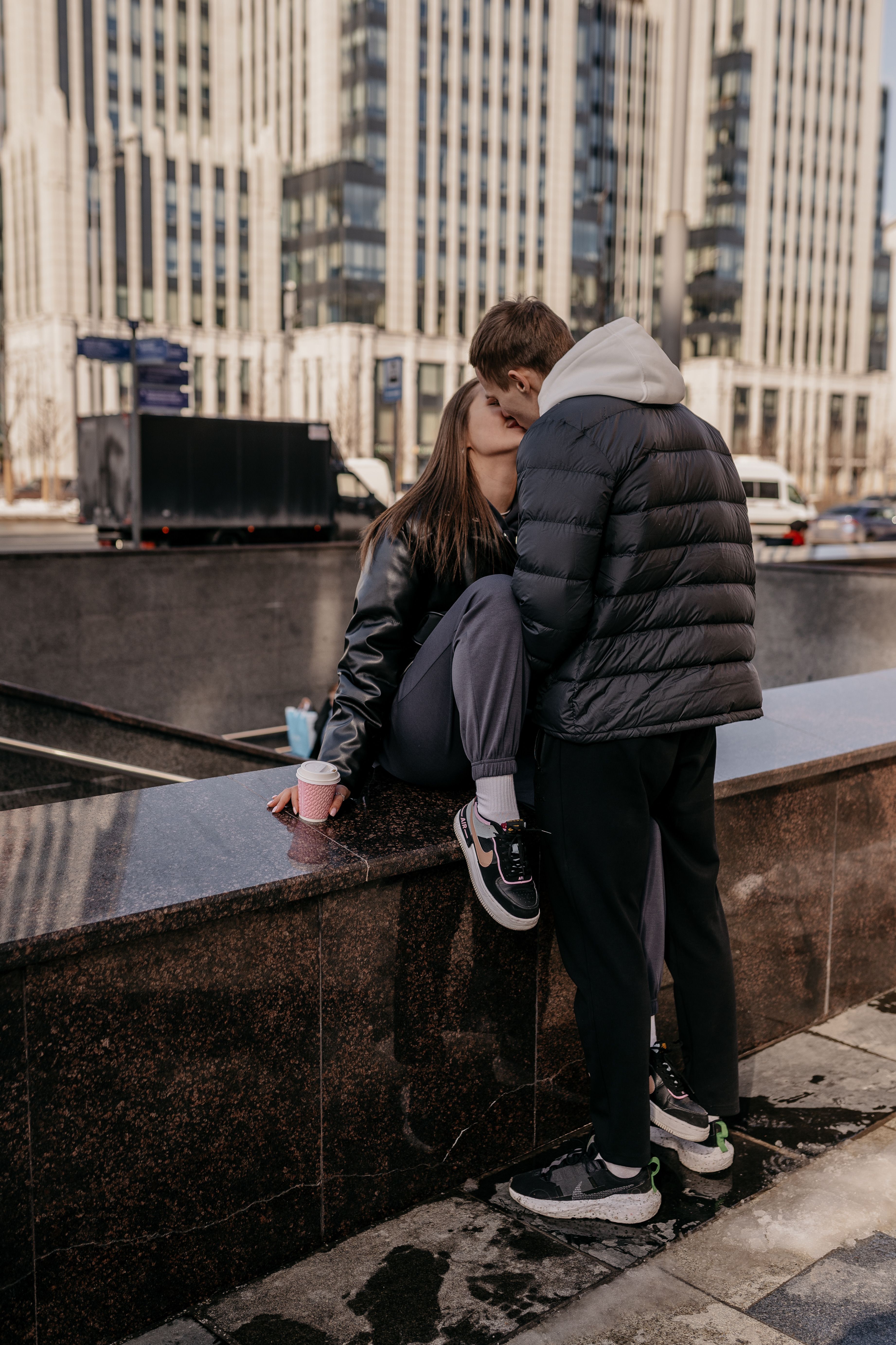 A loving couple shares a kiss in an urban setting, showcasing modern city life.