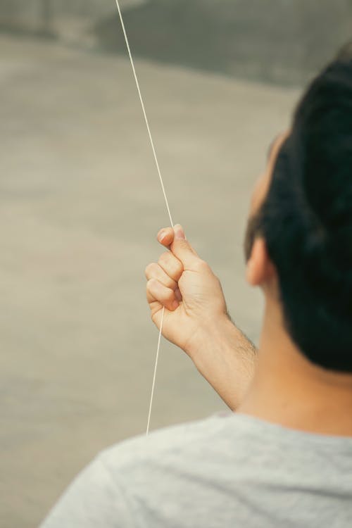 Person Holding a String of a Flying Kite