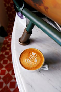 Close-up of a latte with elegant leaf art on a marble table in Ankara, Türkiye.