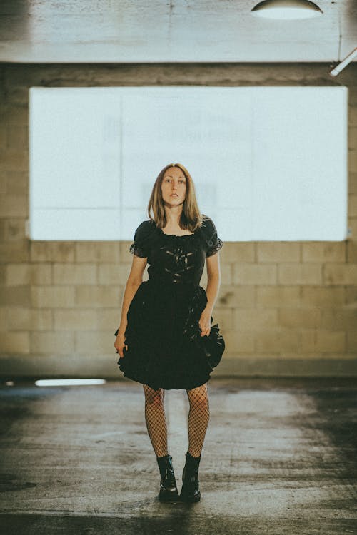 Woman in Black Dress Standing Inside a Building