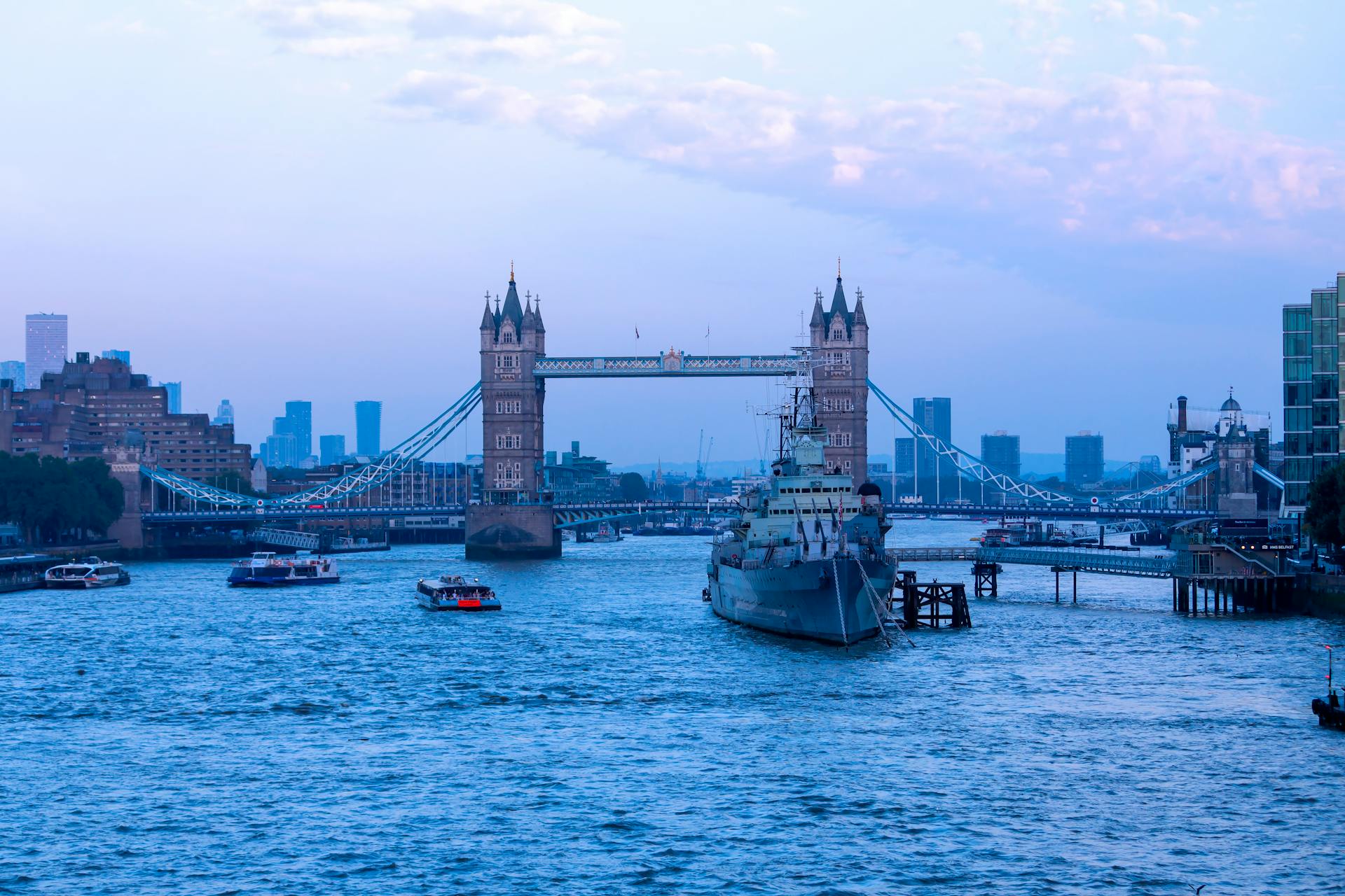 Scenic view of London's Tower Bridge at dusk, featuring the River Thames and cityscape.