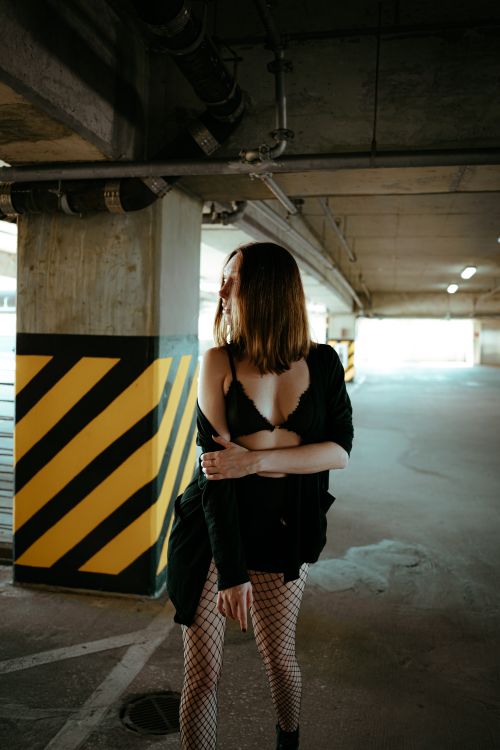 Free Woman in edgy fashion poses in a dimly lit parking garage, embodying urban style. Stock Photo