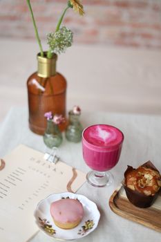 A cozy cafe scene featuring a vibrant pink smoothie, baked goods, and decorative elements.