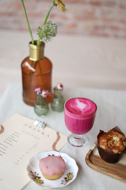 A cozy cafe scene featuring a vibrant pink smoothie, baked goods, and decorative elements.