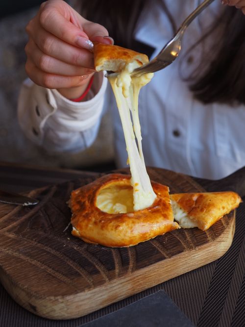 Free Close-up of freshly baked cheese-filled bread with a deliciously gooey cheese pull, perfect for food lovers. Stock Photo