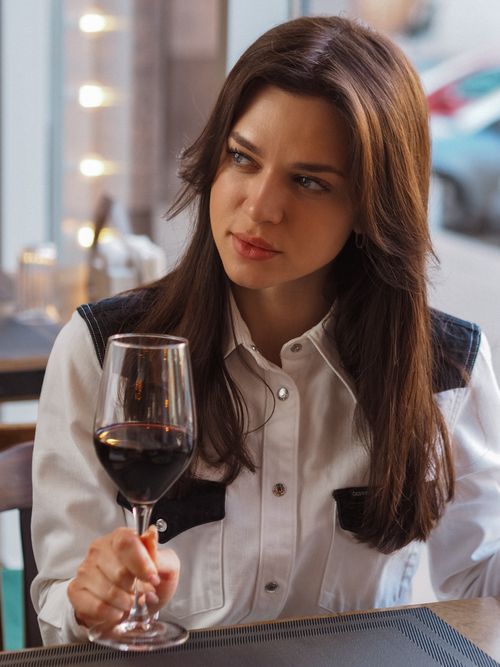 Free Brunette woman savoring red wine at a cafe table indoors. Stock Photo