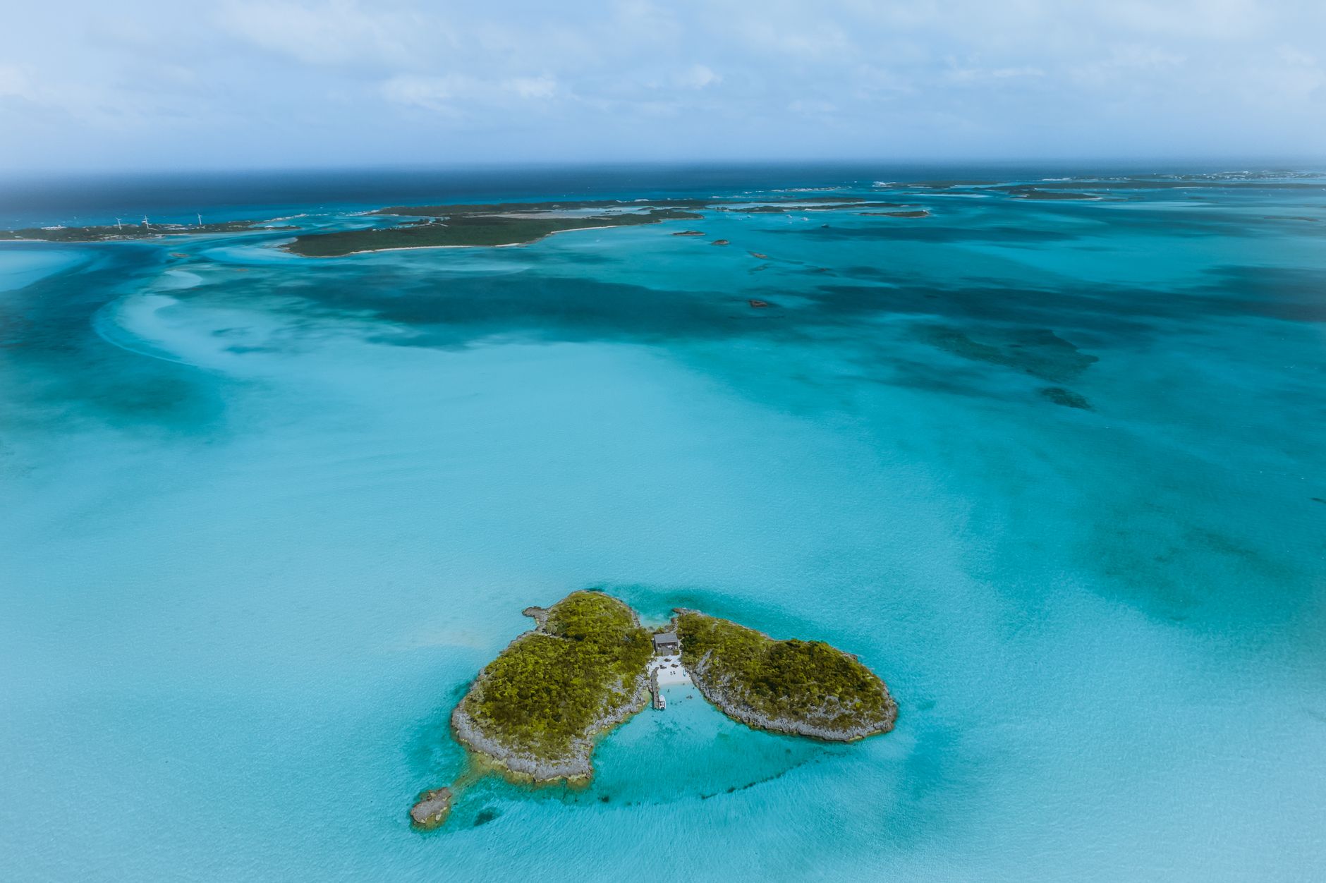 A breathtaking aerial shot of a small tropical island surrounded by crystal-clear turquoise waters.